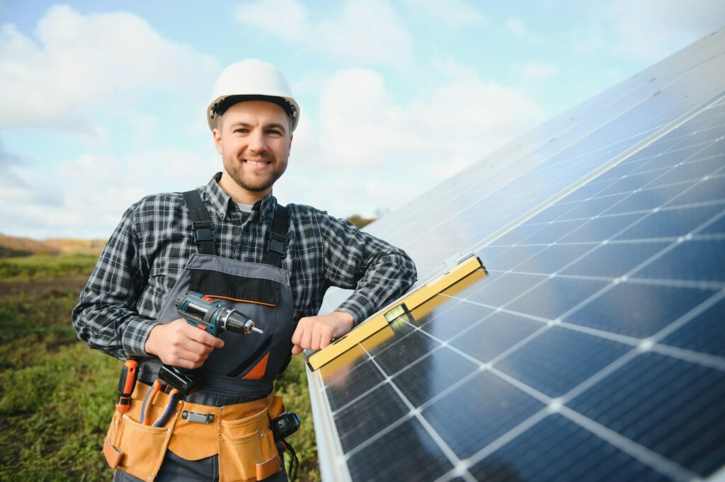 A handyman standing on the rooftop with solar panels and smiling at the camera.